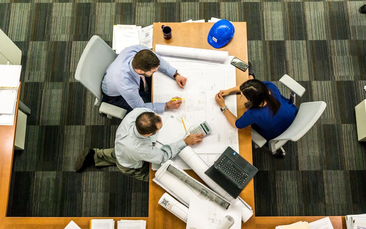 três engenheiros sentados em uma mesa para uma reunião.